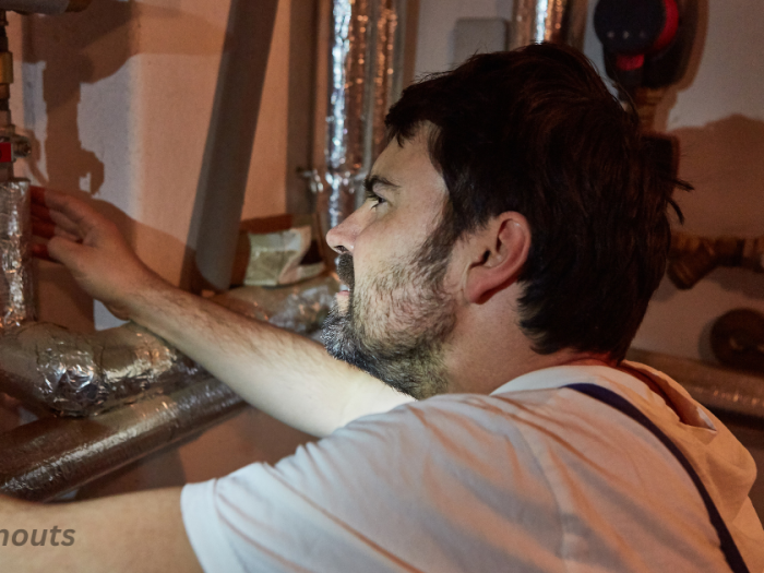 A man putting fireproof insulation around stove pipe